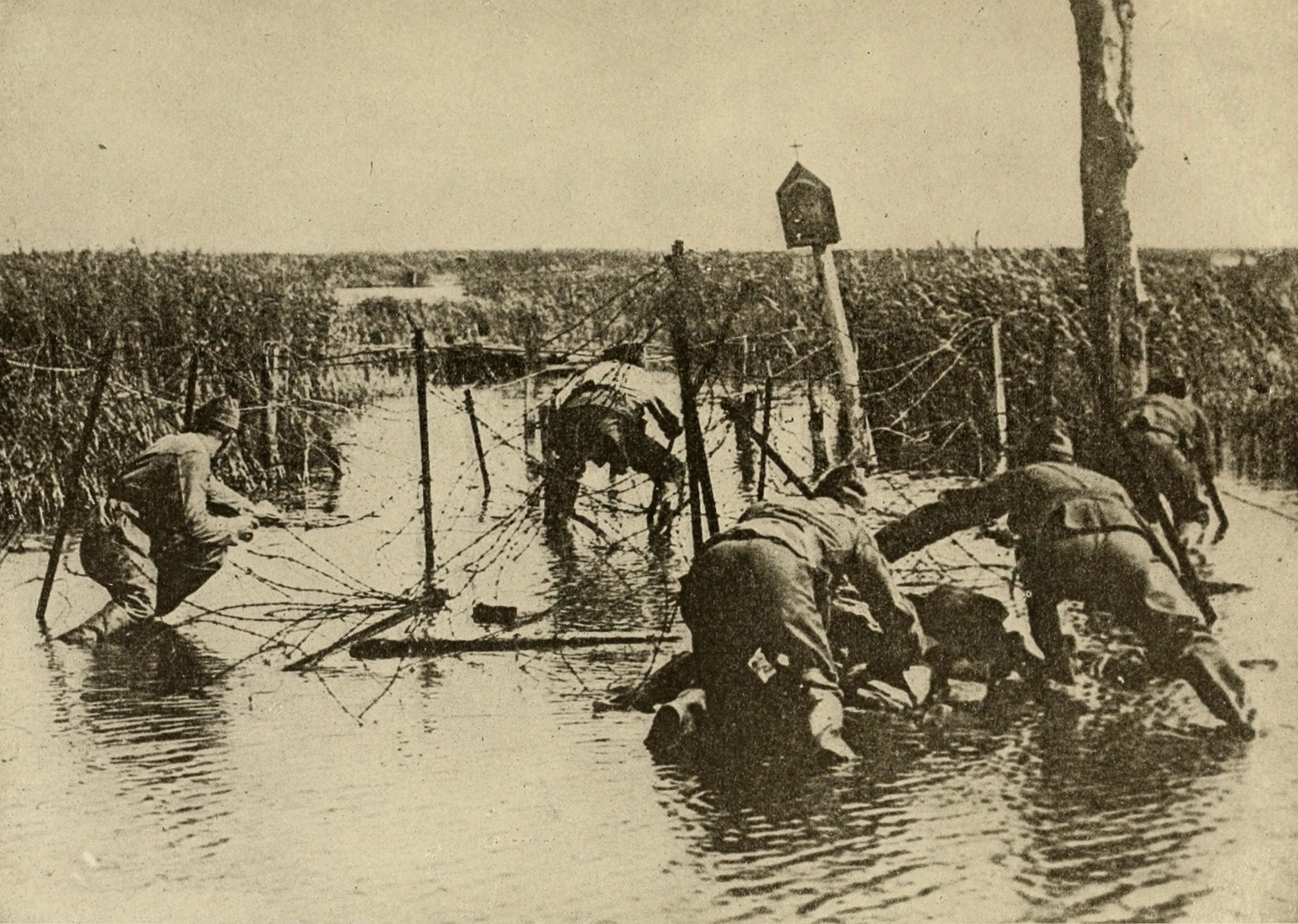 American soldiers struggle to pass multiple lines of barbed wire 